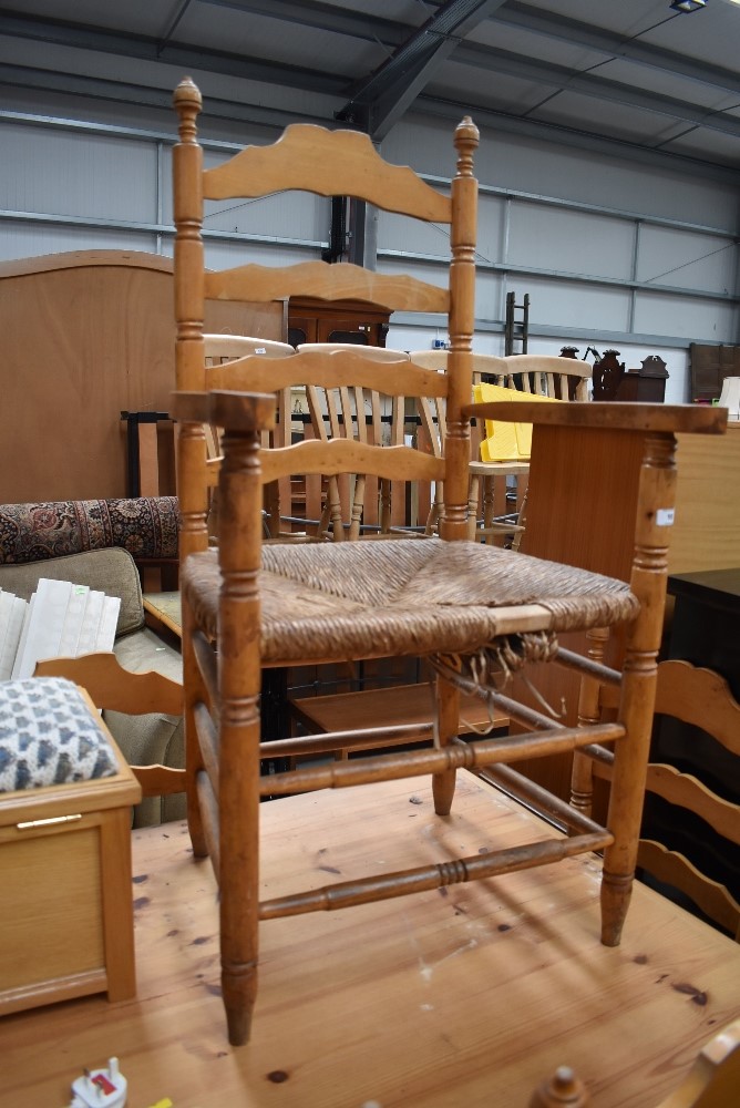 A set of four (three plus one carver) light stained ladder back chairs having rush seats