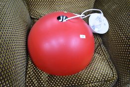 A large ceiling light fitting with red half sphere shade, in the industrial style