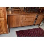 A vintage sapele sideboard of stylised form, three central graduated drawers with brass handles,