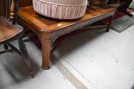 A reproduction mahogany and yew wood coffee table, having canted corners, blind fretwork frieze on