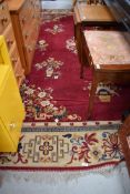 A traditional room sized carpet square, having red ground and floral vase pattern