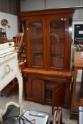 A late Victorian mahogany display case having drawer and under cupboard with rolled glass front