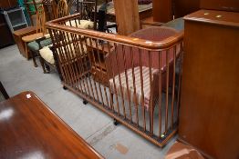 A large nursery style fire fender , having copper upright rails and stained wood top rail, on