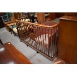 A large nursery style fire fender , having copper upright rails and stained wood top rail, on