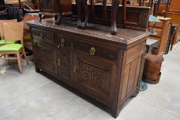 A 19th Century oak sideboard having panelled ledge back, carved drawer and door fronts with brass