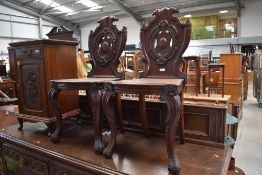 A pair of 19th Century mahogany hall chairs having shield backs, solid seats and scroll legs