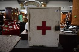 A vintage medical cabinet having red cross to door