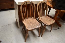 A pair of kitchen chairs with stick backs on elm wood seats