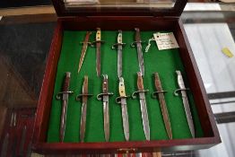 A wood and glass small display case containing a collection of 11 Miniature Bayonets, 10 with