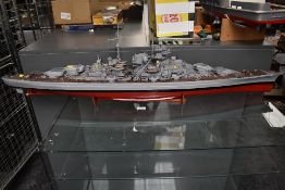 A hand built wooden and plastic scale model of Bismarck, on wood stand, with building