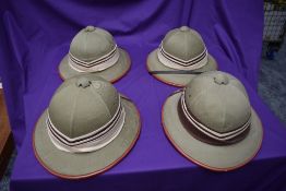 Four Kharki Pith Helmets, size 57, 58, 59 & 60 all with cream and brown band, all with chin straps