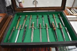 A wood and glass small display case containing a collection of 17 Miniature Bayonets, 4 with