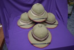 Four Kharki Pith Helmets, size 57, 58, 59 & 60 all with cream and brown band, all with chin straps