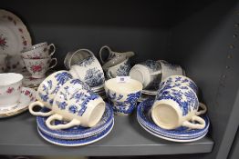 A mixture of blue and white cups,saucers and a jug.