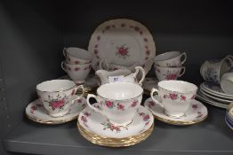 A collection of vintage cups, saucers,cake plate and more, having pink rose pattern and gilt