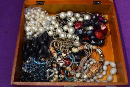 A wooden box containing a selection of costume jewellery necklaces