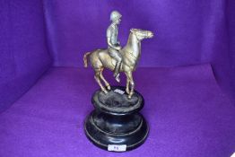 A vintage bronze effect horse and rider mounted on wooden plinth, possibly of military interest.