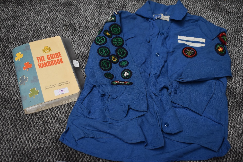 A 1960s girl guides blouse with badges and a copy of the guide book.