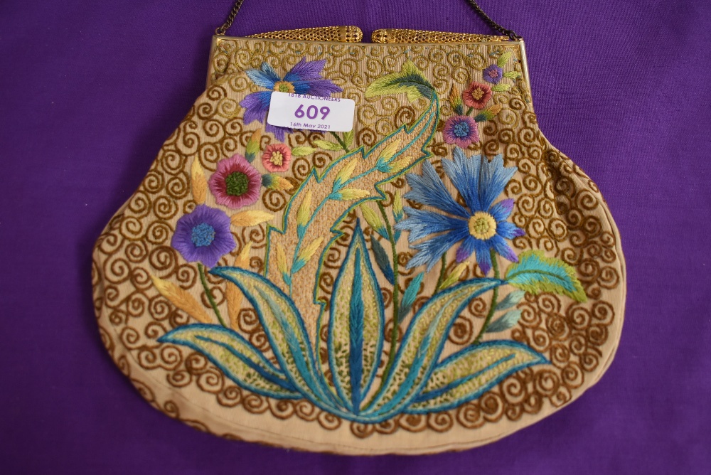 An antique clasp framed evening bag having unusual filigree clasp and colourful floral embroidery to