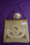 An antique clasp framed evening bag having unusual hinged action which allows the bag to open up