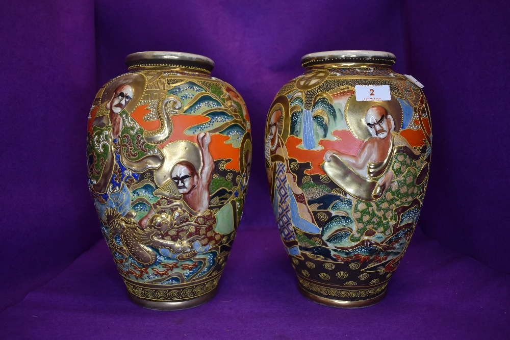 A pair of hand painted Japanese vases having relief moulded pattern possibly depicting the eight