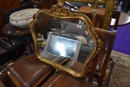 A reproduction gilt effect wall mirror having foliate style shaped frame