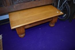 A light stained coffee table, on heavy legs
