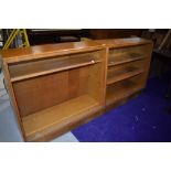 A pair of mid Century golden oak bookcases, having sliding glass doors