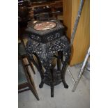 A late 19th or early 20th Chinese hardwood plant stand, extensively carved, with rouge marble inset,