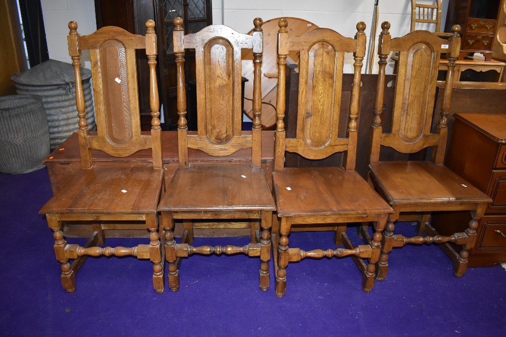 A set of four traditional oak colonial style dining chairs having panel backs and solid seats