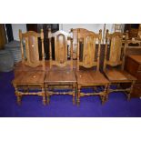 A set of four traditional oak colonial style dining chairs having panel backs and solid seats