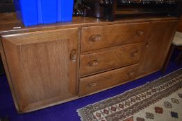 A mid stain Ercol sideboard having three central drawers , flanked by cupboard, on shepherds