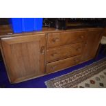 A mid stain Ercol sideboard having three central drawers , flanked by cupboard, on shepherds