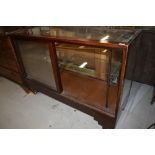 A vintage stained frame and glazed shop counter having sliding doors, width approx 137cm, some