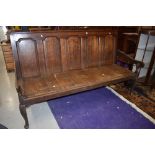 An 18th Century oak settle having five panelled back , shaped arms and cabriole legs, width