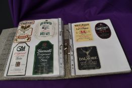 A folder containing 1980's and later Wine, Whisky, Champagne and similar paper labels, most glued d