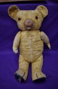 A mid 20th century straw filled teddy bear having plastic eyes, rubber nose and mouth, padded paws