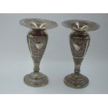 A pair of white metal bud vases having extensive floral repousse panels with plain cartouche and