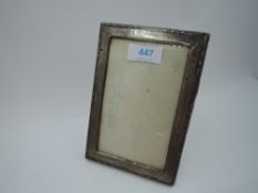 A small silver photograph frame of rectangular form having moulded decoration and wooden back with