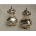 A pair of Edwardian silver pepperettes of baluster form having moulded decoration and push on