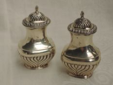 A pair of Edwardian silver pepperettes of baluster form having moulded decoration and push on