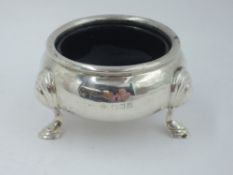 A silver salt cellar of plain cauldron form having trefoil hoof feet and blue glass liner, London