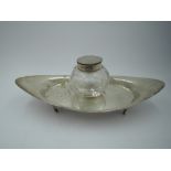 An Edwardian silver inkwell stand of plain boat form on quatrefoil bracket feet with cut glass