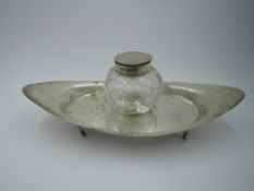 An Edwardian silver inkwell stand of plain boat form on quatrefoil bracket feet with cut glass