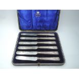 A cased set of six Edwardian silver handled dessert knives having moulded handles with scallop shell