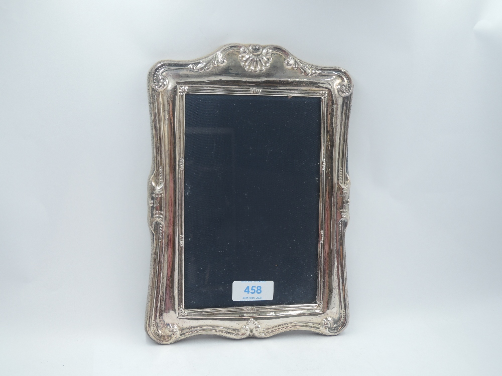 A silver photograph frame having moulded arched decoration and blue velvet back, missing easel