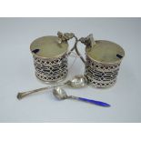 A pair of silver mustard pots of cylindrical form having pierced decoration, hinged lids and blue