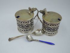 A pair of silver mustard pots of cylindrical form having pierced decoration, hinged lids and blue