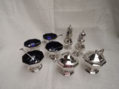 An eight piece silver condiment set of plain facetted octagonal form with blue glass liners and 6