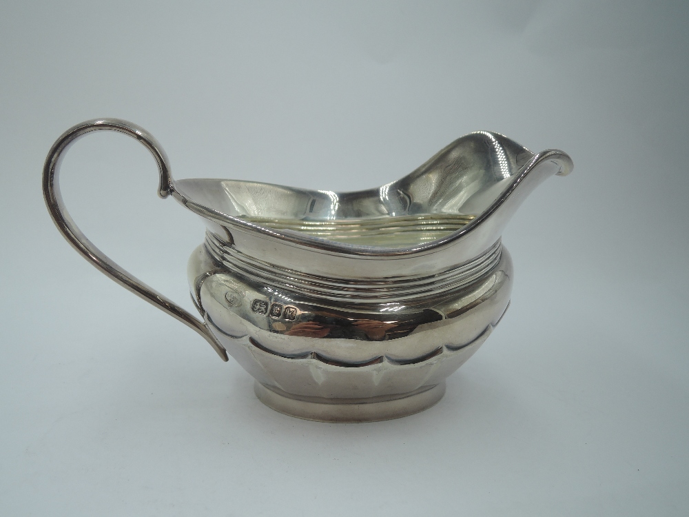 A silver cream jug having facetted decoration, rub over rim and loop handle, London 1945, makers